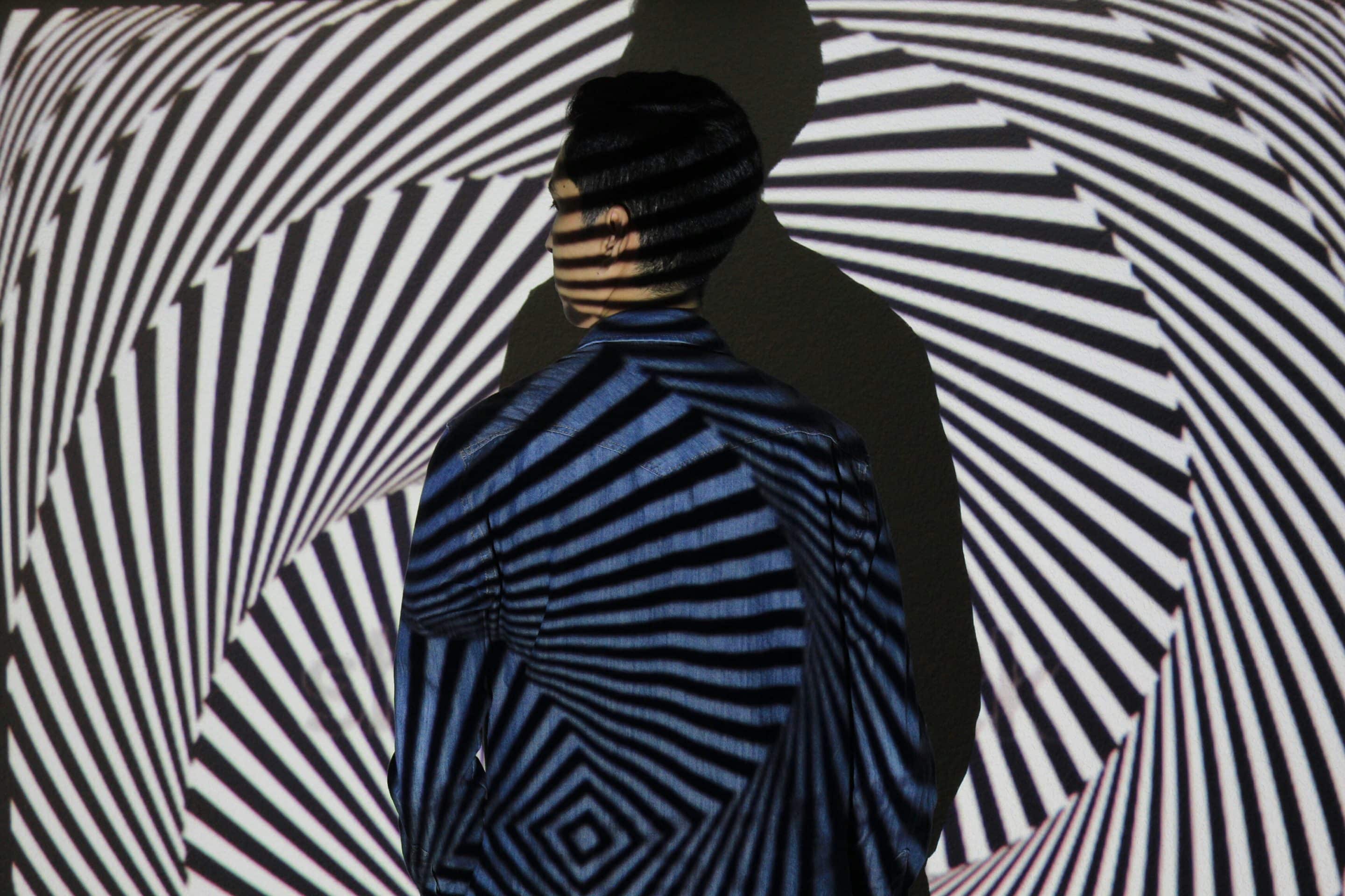 rear view man standing by wall with light shadow